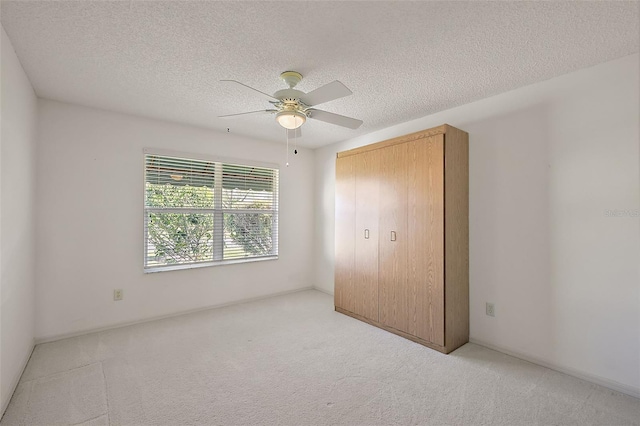 unfurnished bedroom featuring a closet, a textured ceiling, a ceiling fan, and carpet flooring