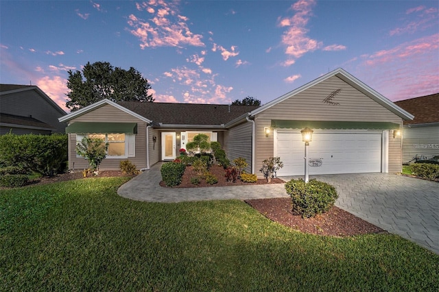 ranch-style home featuring a lawn, an attached garage, and decorative driveway