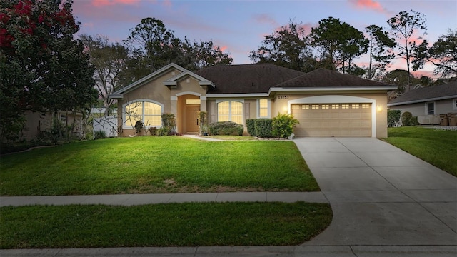 single story home with a garage, a front lawn, concrete driveway, and stucco siding