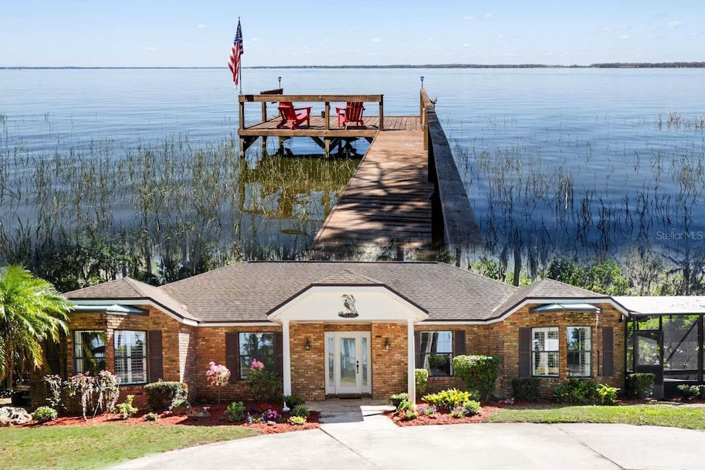 view of front of house featuring brick siding, a boat dock, and a water view