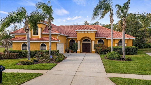 mediterranean / spanish-style home with a garage, a front yard, concrete driveway, and stucco siding