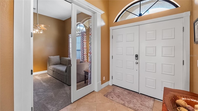 entryway with light carpet, light tile patterned floors, and baseboards