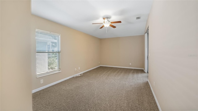 carpeted spare room with a ceiling fan, visible vents, and baseboards