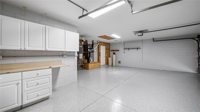 garage with concrete block wall, gas water heater, and a garage door opener