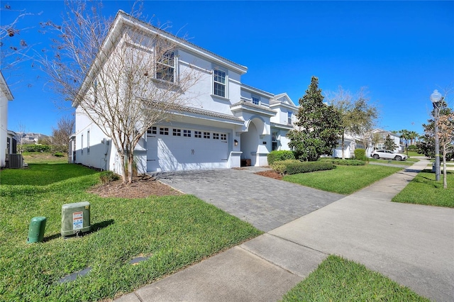 traditional home featuring a front lawn, decorative driveway, an attached garage, and stucco siding