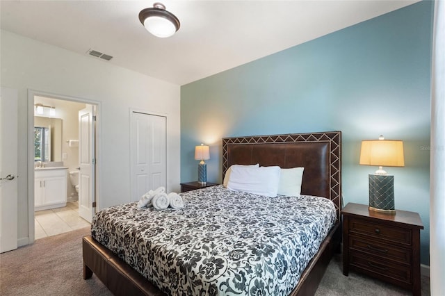 bedroom featuring light tile patterned floors, a closet, light colored carpet, visible vents, and connected bathroom