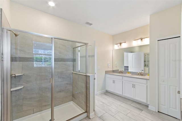 bathroom featuring double vanity, a shower stall, visible vents, and a sink