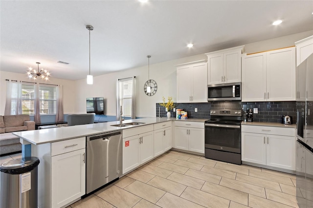 kitchen with stainless steel appliances, light countertops, open floor plan, a sink, and a peninsula