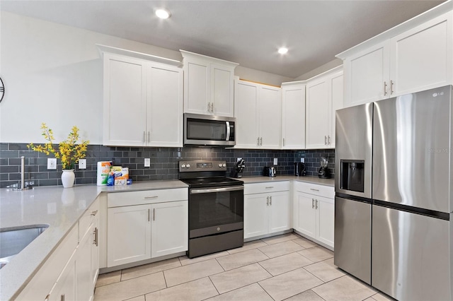 kitchen featuring light tile patterned floors, appliances with stainless steel finishes, backsplash, and white cabinetry