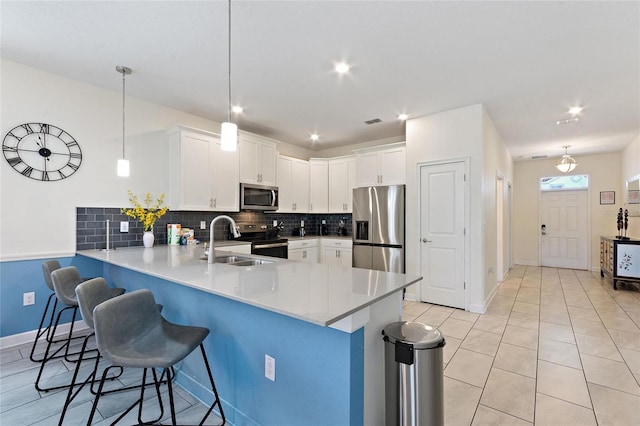 kitchen featuring a peninsula, stainless steel appliances, backsplash, and a kitchen breakfast bar