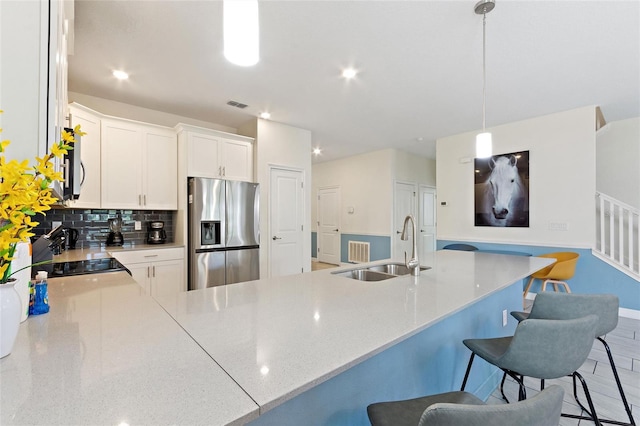 kitchen featuring stainless steel appliances, a peninsula, a sink, visible vents, and backsplash