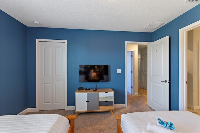 carpeted bedroom with a textured ceiling, a closet, visible vents, and baseboards