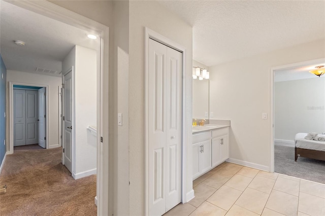 ensuite bathroom with baseboards, visible vents, a closet, and vanity