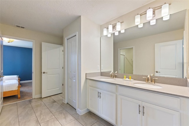 bathroom featuring a textured ceiling, double vanity, an enclosed shower, and a sink