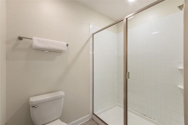 full bath featuring baseboards, a shower stall, and toilet