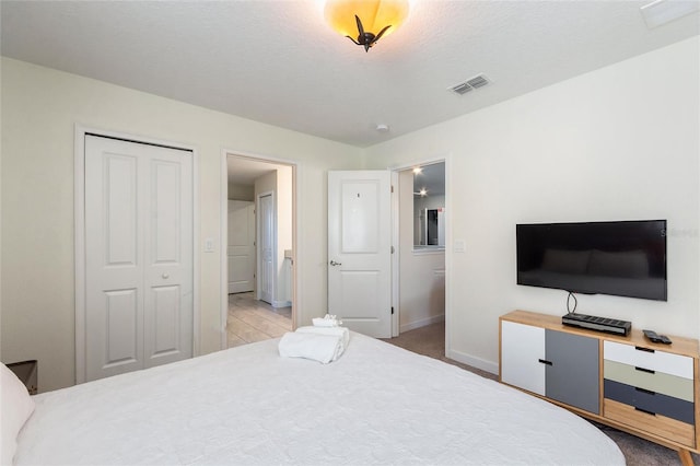 bedroom featuring baseboards, a textured ceiling, visible vents, and a closet