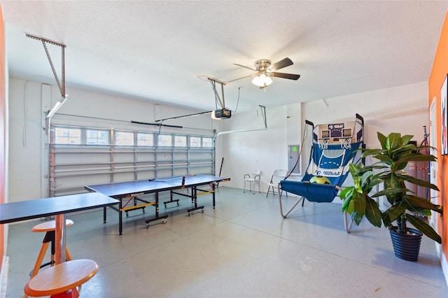 rec room featuring a garage, speckled floor, a textured ceiling, and a ceiling fan