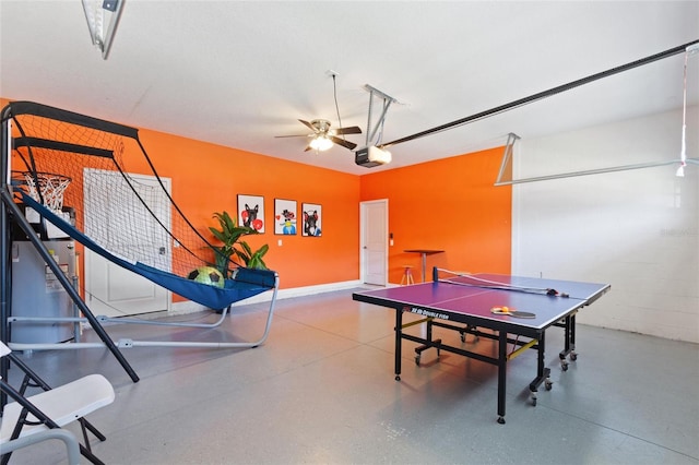 rec room featuring concrete block wall, ceiling fan, a garage, and speckled floor