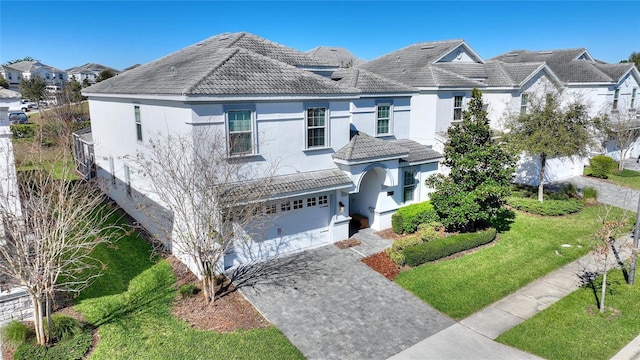 view of front of home featuring an attached garage, a tile roof, decorative driveway, and stucco siding