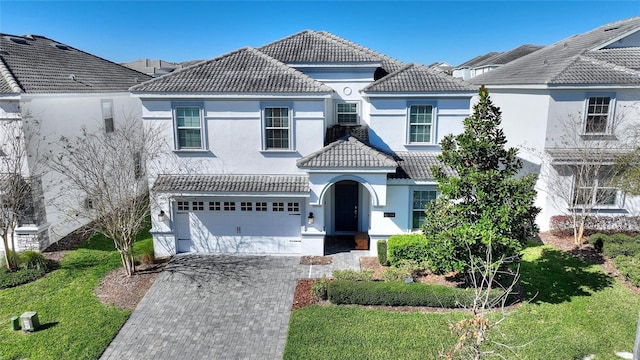 view of front of home featuring a garage, decorative driveway, a tiled roof, and stucco siding