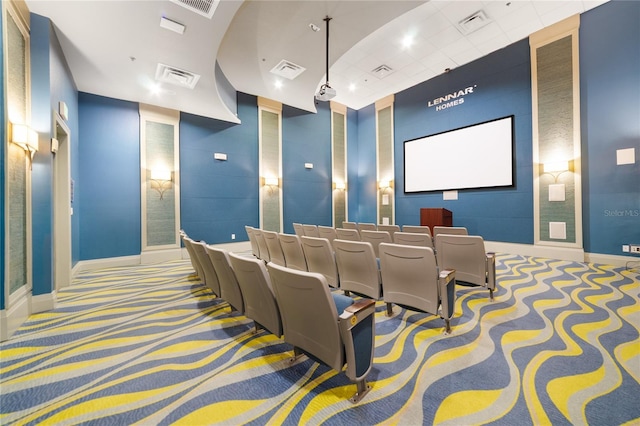 cinema room with carpet, visible vents, and baseboards