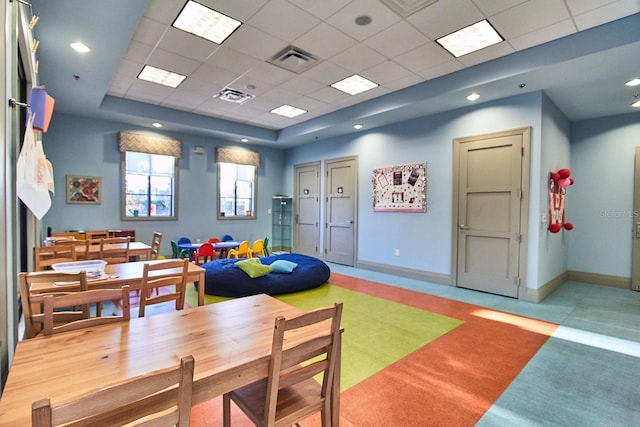 rec room featuring a tray ceiling, a drop ceiling, visible vents, and baseboards