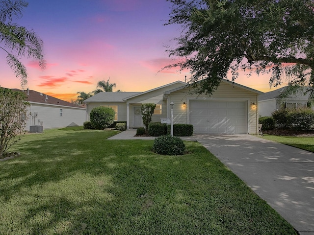 view of front of house featuring a garage, concrete driveway, a yard, and central AC