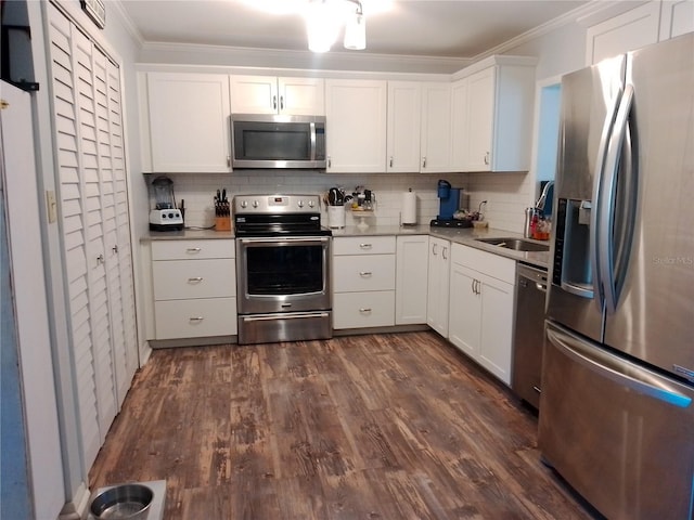 kitchen featuring decorative backsplash, ornamental molding, dark wood-type flooring, stainless steel appliances, and white cabinetry