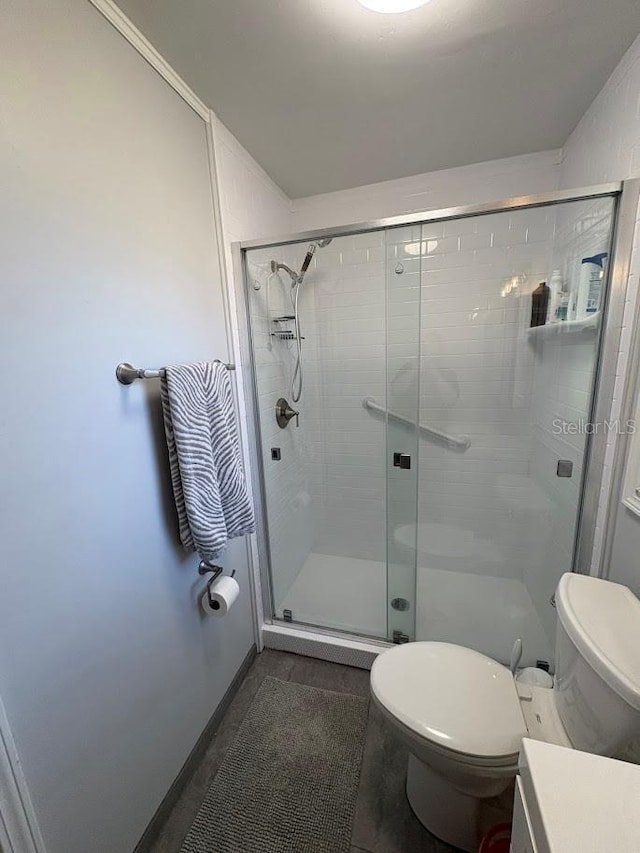 bathroom with vanity, a shower stall, and toilet