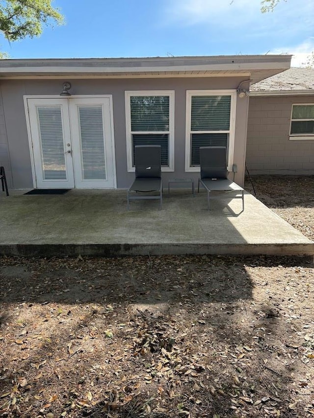 view of exterior entry with a patio area, concrete block siding, and french doors