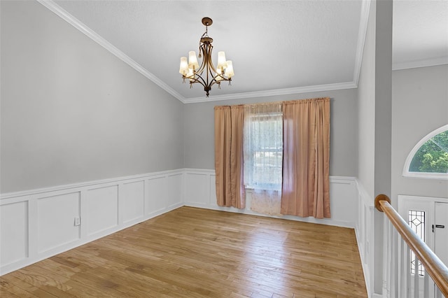 16017 Harbar Oaks Dr, Montverde, FL 34756 - unfurnished room with a chandelier, crown molding, light wood-style flooring, wainscoting, and a decorative wall