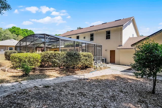 16017 Harbar Oaks Dr, Montverde, FL 34756 - back of house featuring stucco siding, a lanai, central air condition unit, and roof with shingles