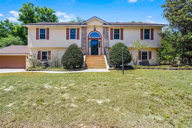 16017 Harbar Oaks Dr, Montverde, FL 34756 - raised ranch featuring stucco siding, a front lawn, a garage, and concrete driveway
