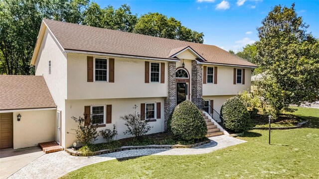 16017 Harbar Oaks Dr, Montverde, FL 34756 - split foyer home with a front lawn, stucco siding, and roof with shingles