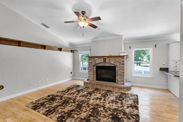 16017 Harbar Oaks Dr, Montverde, FL 34756 - unfurnished living room featuring lofted ceiling, light wood-style floors, ceiling fan, a brick fireplace, and a textured ceiling