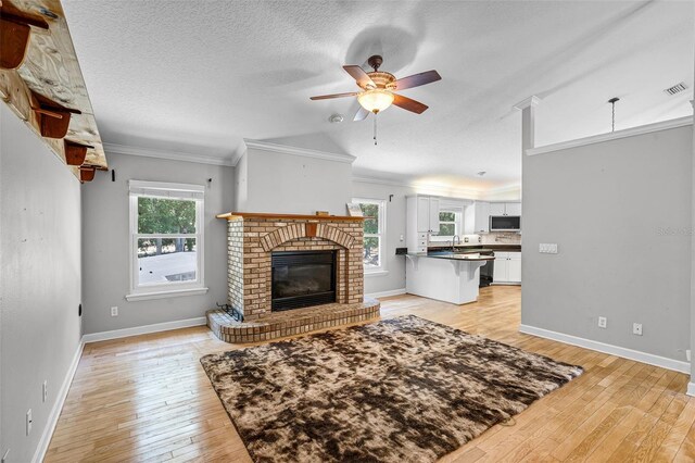 16017 Harbar Oaks Dr, Montverde, FL 34756 - living area featuring a brick fireplace, light wood-style flooring, ceiling fan, baseboards, and crown molding