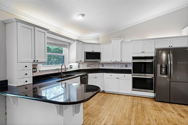 16017 Harbar Oaks Dr, Montverde, FL 34756 - kitchen featuring stainless steel appliances, a sink, ornamental molding, a textured ceiling, and dark countertops