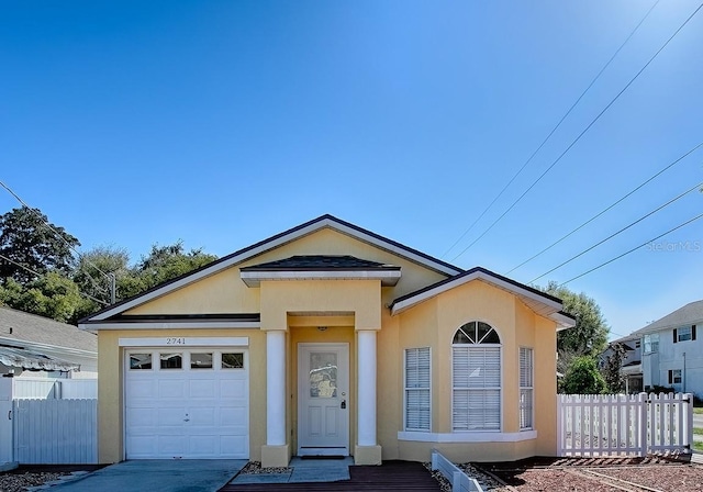 view of front facade featuring stucco siding, an attached garage, and fence