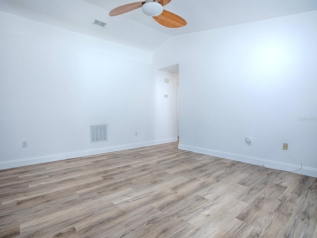 empty room with visible vents, lofted ceiling, light wood-style floors, and baseboards