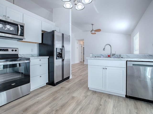 kitchen featuring light wood finished floors, lofted ceiling, white cabinets, stainless steel appliances, and a sink