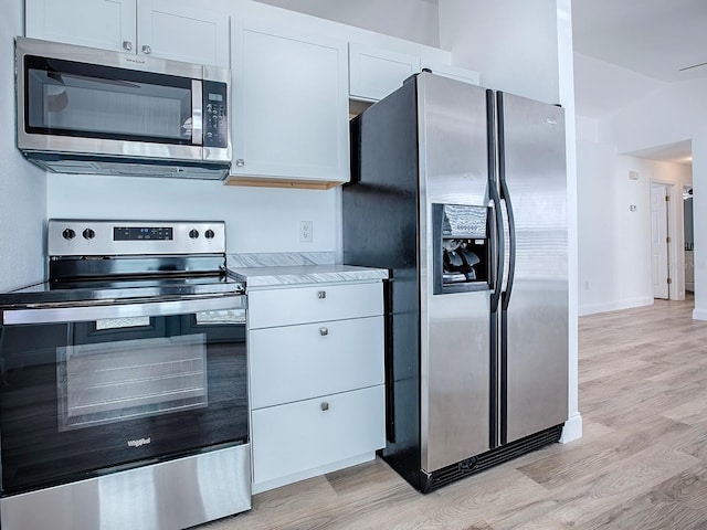 kitchen with white cabinetry, appliances with stainless steel finishes, light wood-style flooring, and light countertops