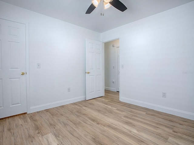 spare room with light wood-style flooring, a ceiling fan, and baseboards