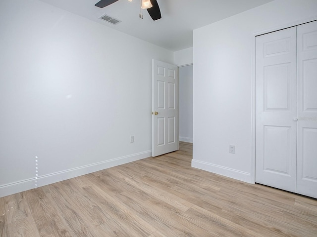 unfurnished bedroom with light wood-type flooring, visible vents, a closet, baseboards, and ceiling fan