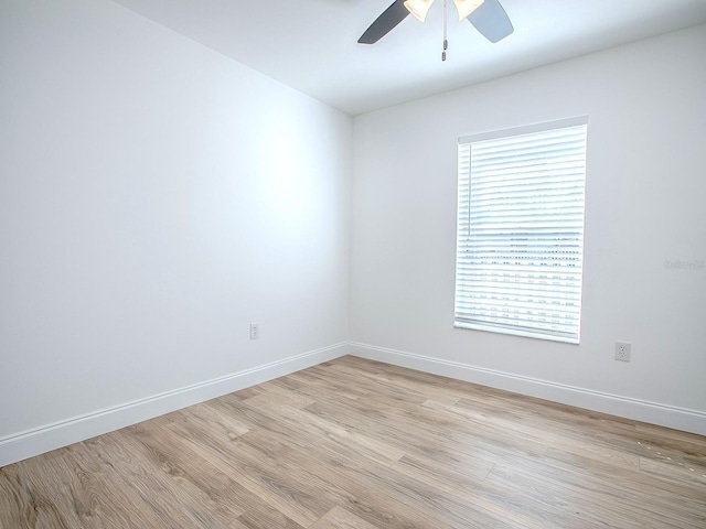 spare room with baseboards, light wood-style floors, and a ceiling fan