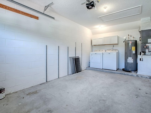 garage with water heater, washing machine and dryer, a garage door opener, and concrete block wall