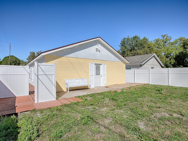 back of property with a fenced backyard, a lawn, concrete block siding, and a deck