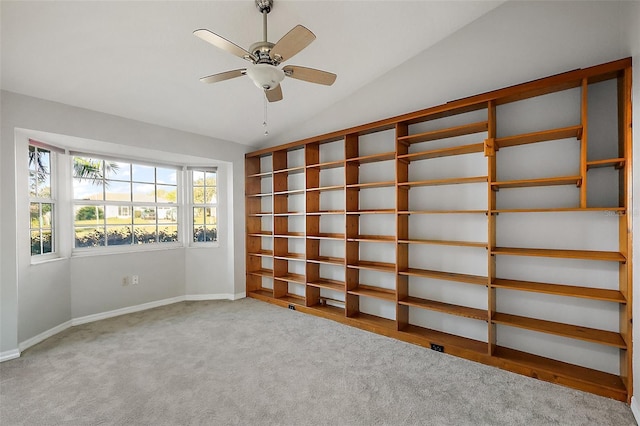 unfurnished room featuring carpet, baseboards, vaulted ceiling, and a ceiling fan