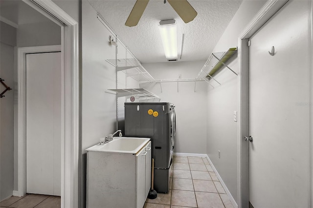 clothes washing area with laundry area, light tile patterned floors, ceiling fan, washing machine and clothes dryer, and a textured ceiling