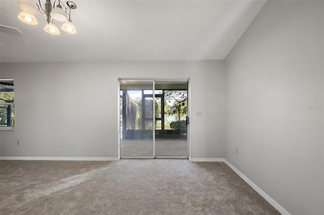 carpeted spare room with a chandelier and baseboards