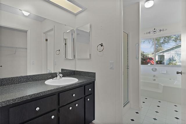 full bath featuring vanity, a stall shower, a walk in closet, tile patterned floors, and a bath